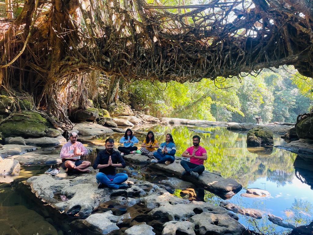 Travellers doing namaste under a living root bridge in Meghalaya