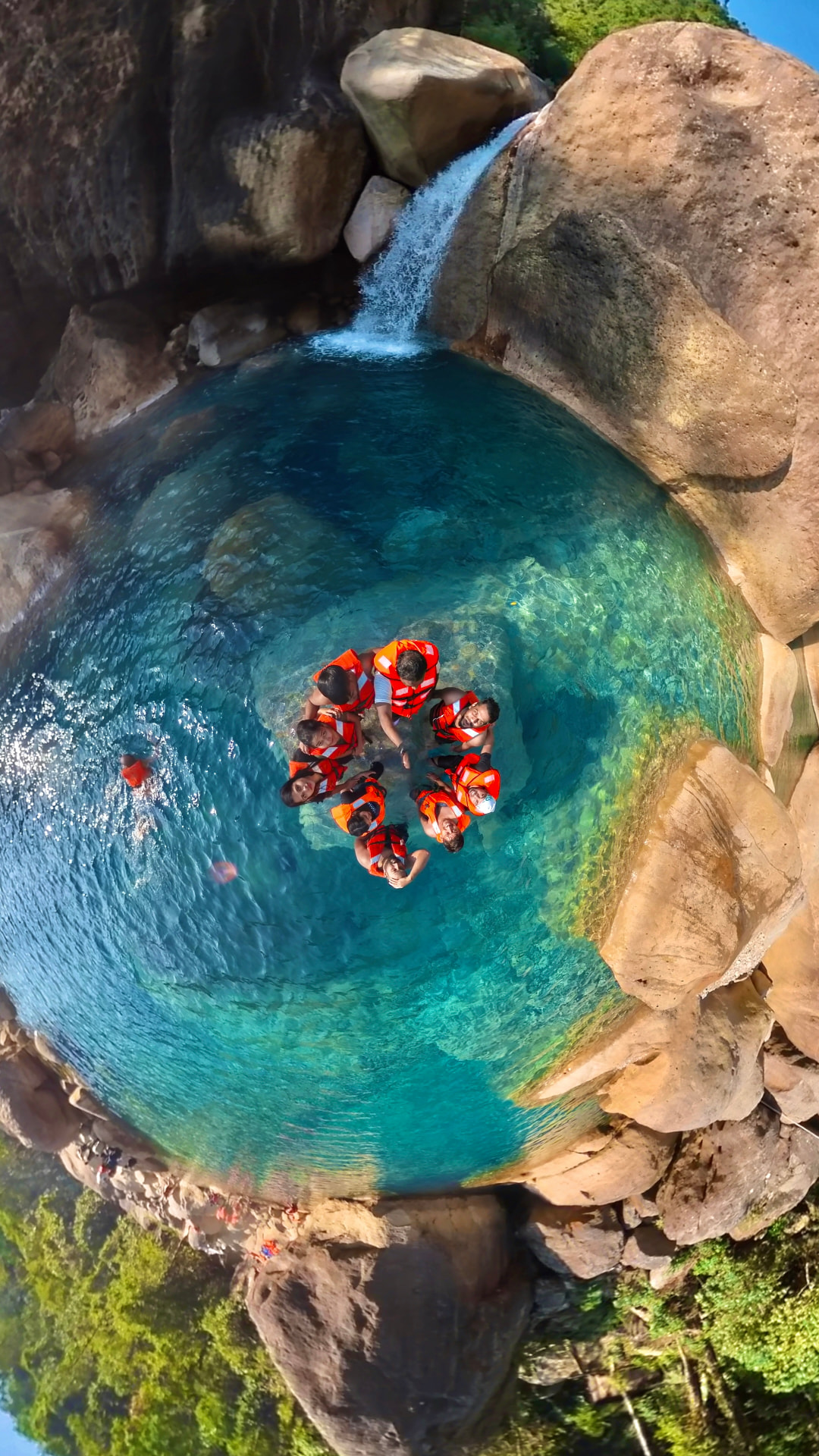Travellers swimming in a natural pool under a waterfall in Meghalaya
