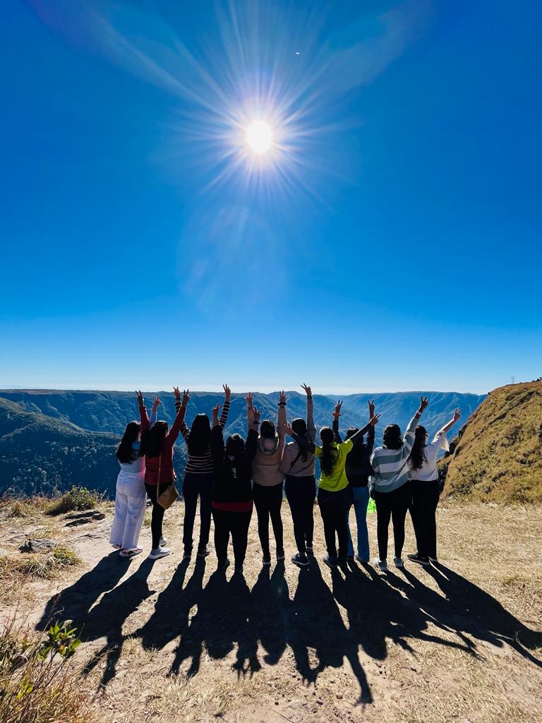 Group of travellers raising their hands at a canyon viewpoint in Meghalaya
